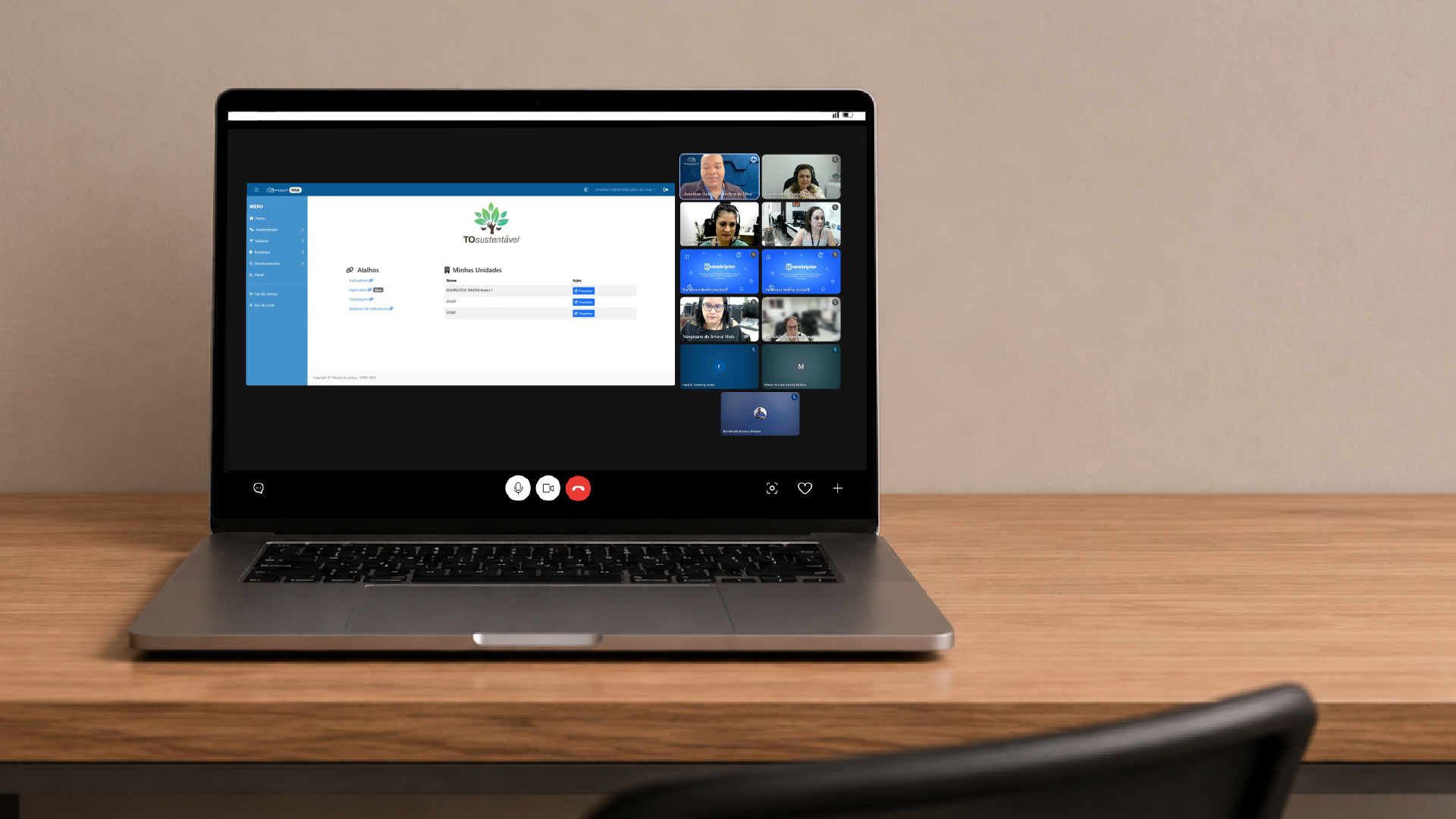 A imagem mostra um notebook sobre uma mesa exibindo uma reunião on-line, durante apresentação do Sistema SIGA/TOSustentável para representantes do Tribunal de Justiça de Rondônia. Na tela, participantes acompanham a videoconferência enquanto são apresentados os painéis e funcionalidades do sistema de gestão socioambiental do TJTO.