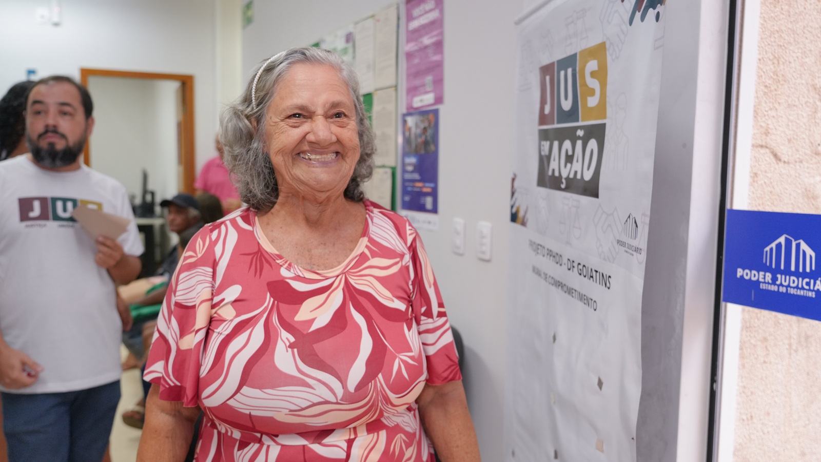 Imagem mostra mulher com vestido florido na cor vermelho e branco em corredor de prédio do fórum de Ponte Alta do Tocantins
