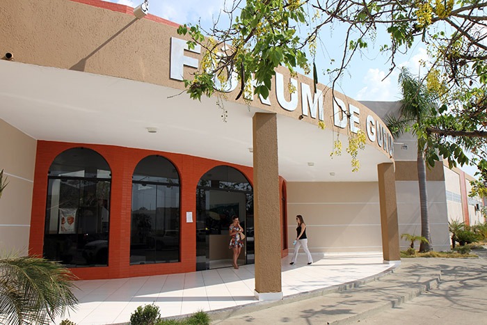 fachada do forum da comarca de gurupi com arvores em frente. o prédio tem as cores branca, bege, laranja. possui vitrais cor escura
