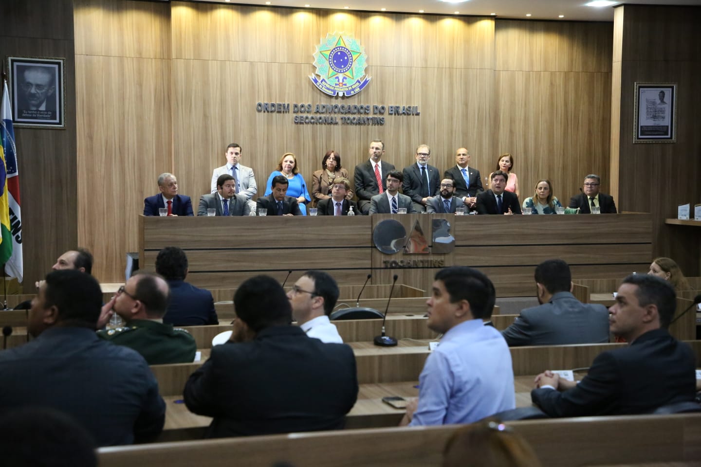 Imagem mostra várias pessoas em um auditório e na mesa várias pessoas, incluindo a desembargadora Ângela Prudente, prestigiam evento dos 30 anos da AGU