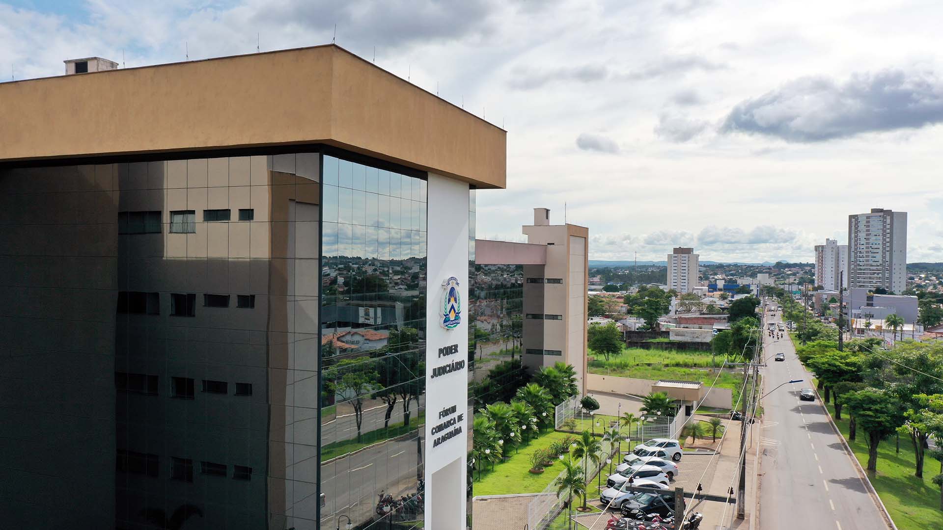 Fachada lateral do prédio que abriga o fórum sede da Comarca de Araguaína, com parte do telhado, lateral espelhada e visão parcial do estacionamento