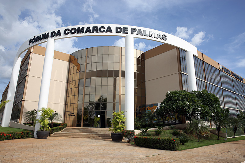 Imagem de prédio banco com vidraças espelhadas; céu azul e nuvens brancas