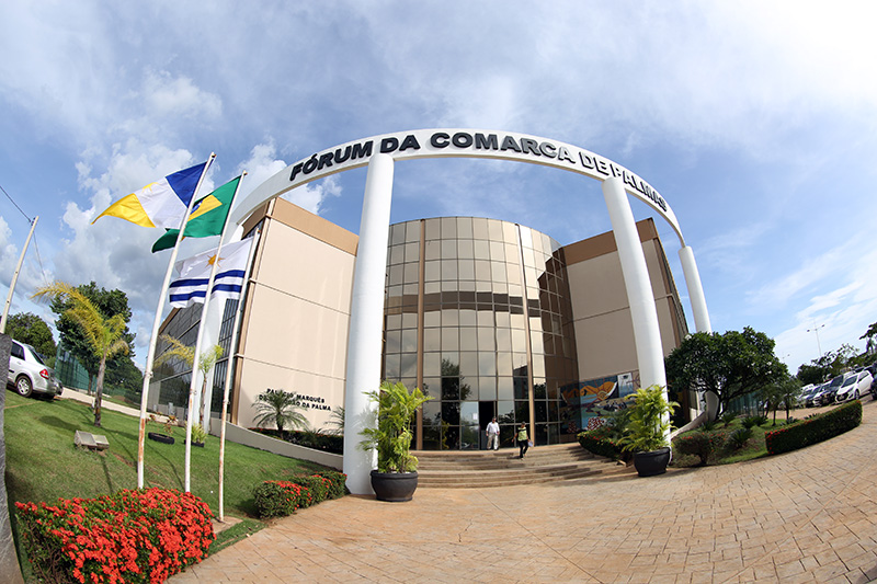 Fachada do Fórum da Comarca de Palmas; paredes pintadas de bege e marrom, vidraças e um arco com o nome Fórum da Comarca de Palmas