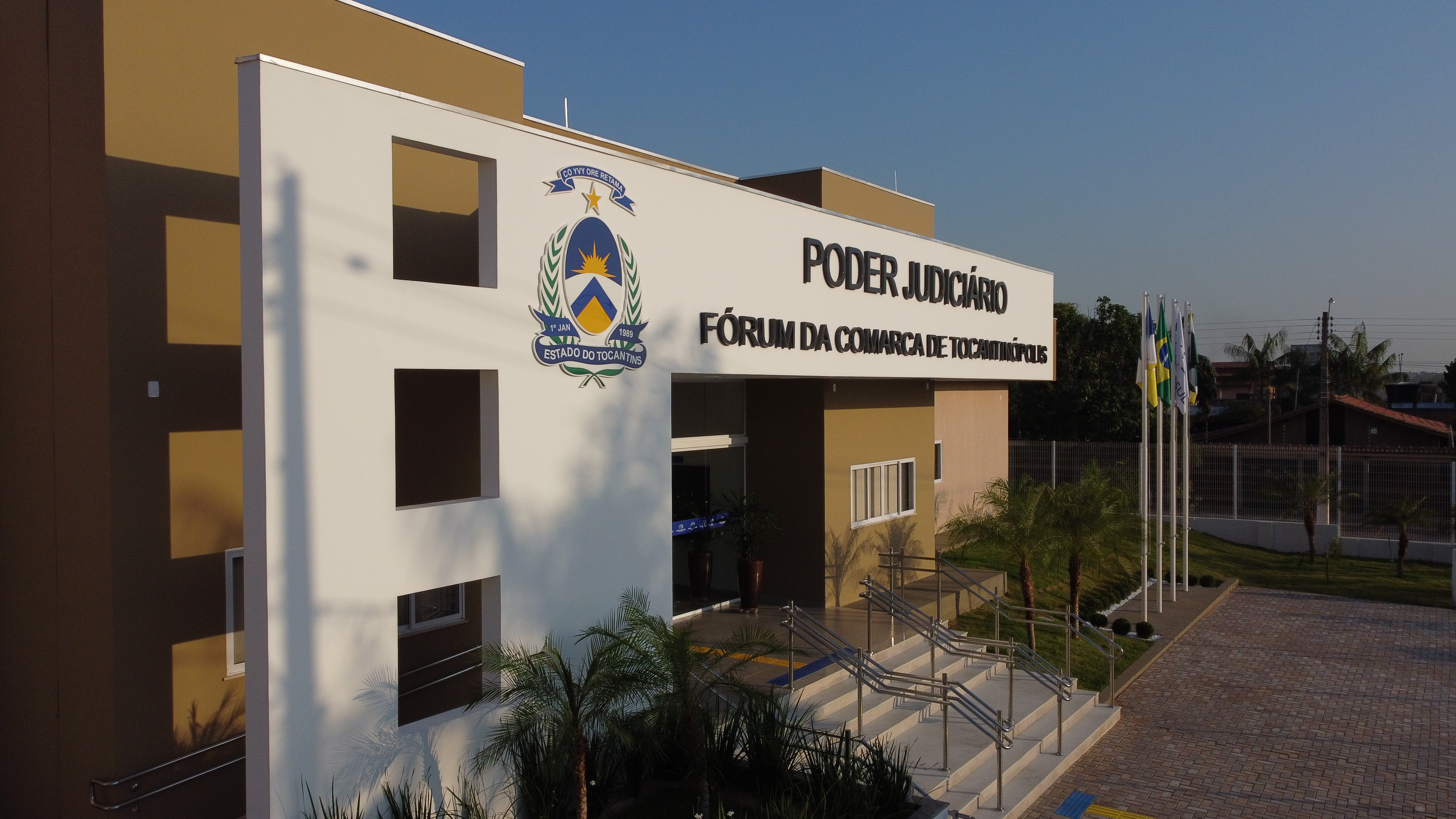 Detalhe lateral da fachada do prédio de Tocantinópolis com pórtico e partes das paredes laterais na cor branca e letreiro com o nome do fórum na cor preta