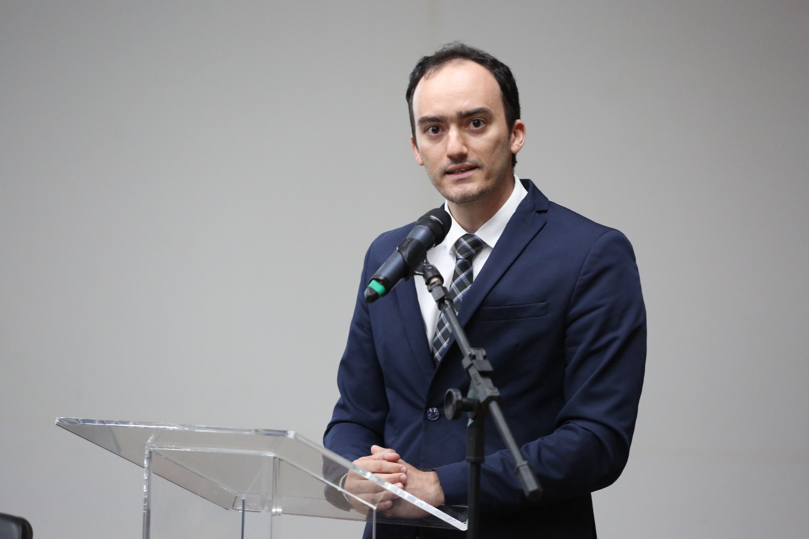 Homem branco, cabelo preto e terno preto fala ao microfone