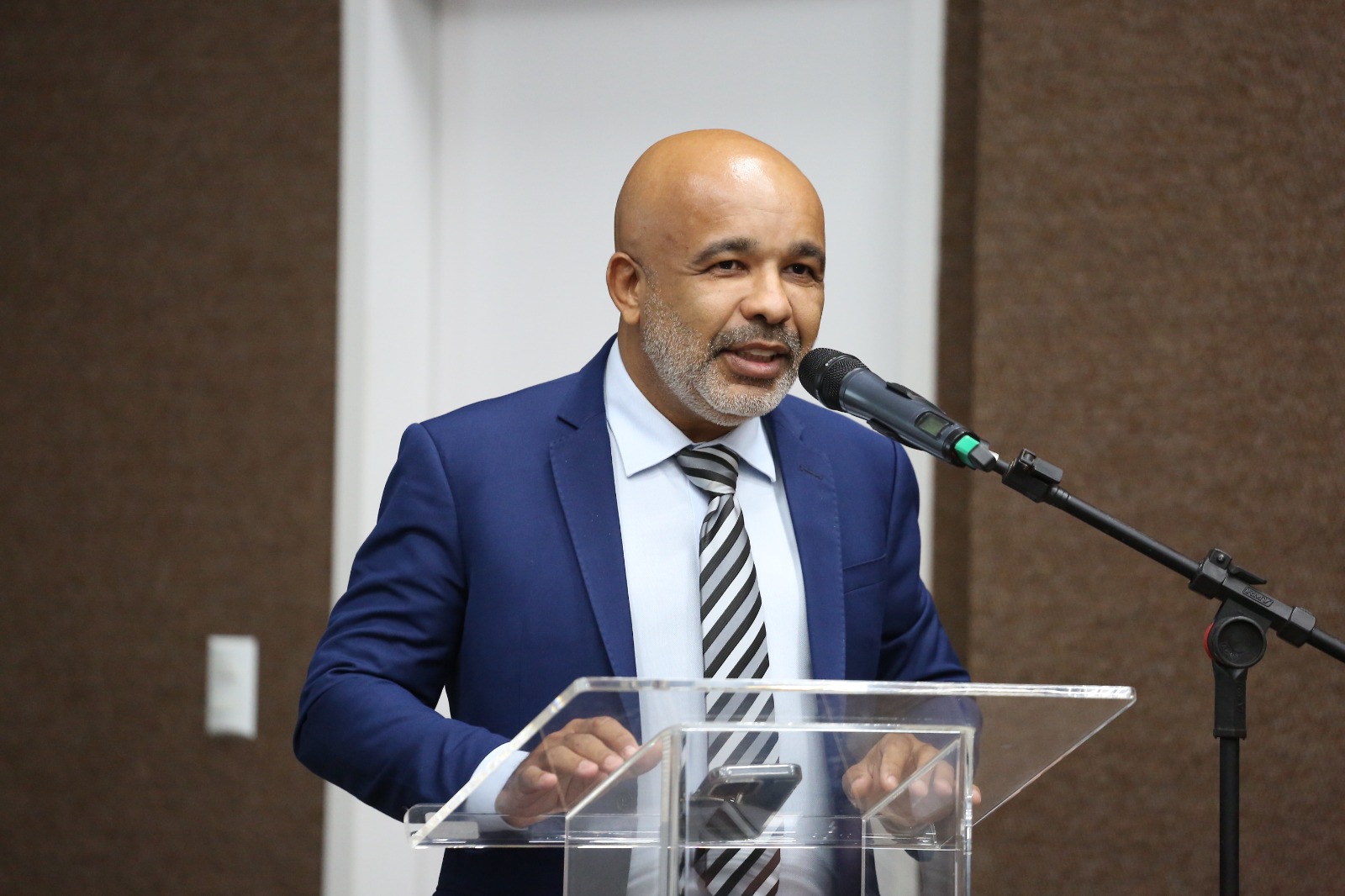 Homem negro com barba branca e terno azul marinho fala ao microfone