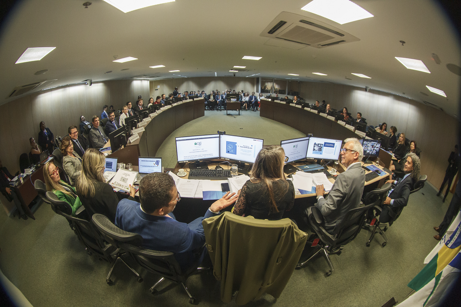 Vista dos participantes da reunião do I Encontro Nacional dos Centros Locais de Inteligência ao redor de uma grande mesa circular, em imagem registrada com o efeito olho de peixe