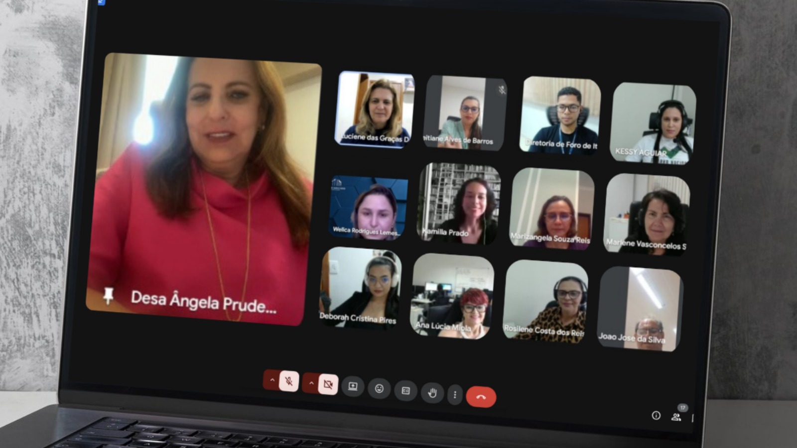 Reunião virtual exibida na tela de um notebook, com uma participante em destaque e demais pessoas em miniaturas.