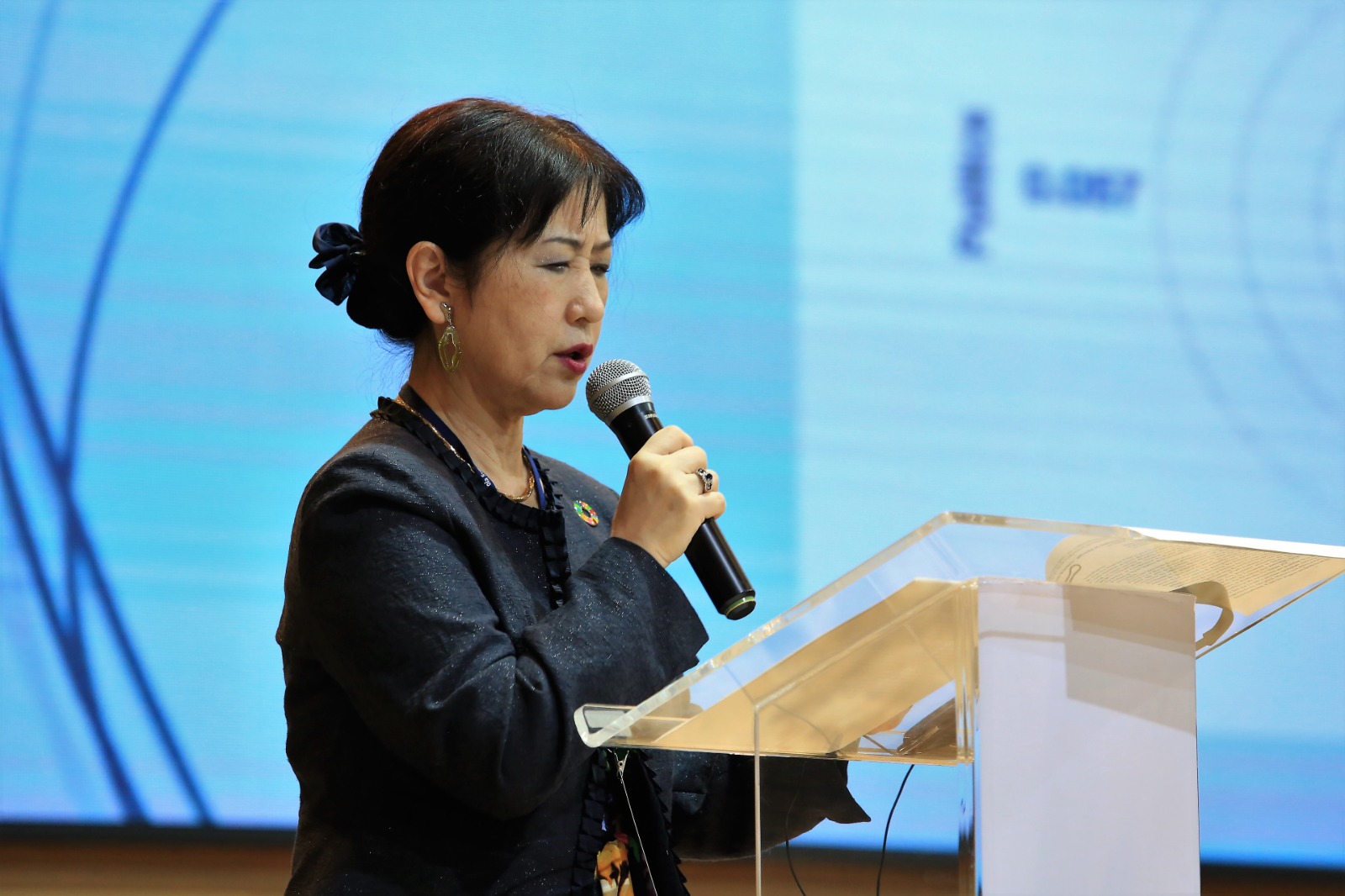 Mana Shimaoka, japonesa, de blusa escura, fala ao microfone, no pulpito