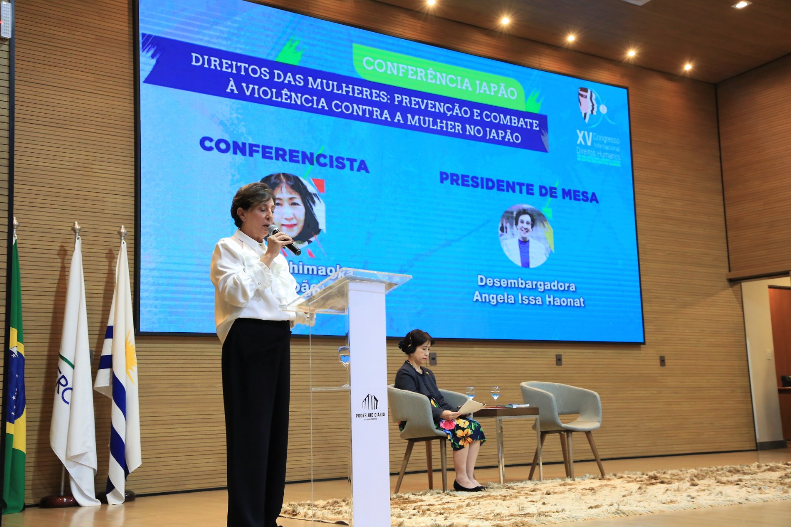 desembargadora Angela Haonat, de blusa branca e calça preta, falando ao microfone