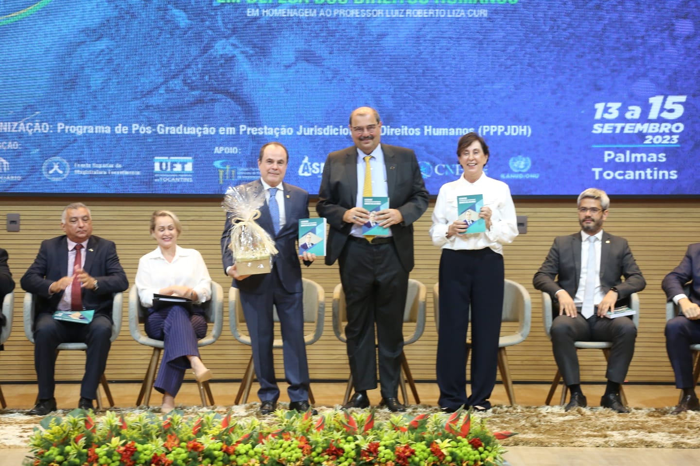 desembargador Marco Villas Boas no palco, juntamente com a desembargadora Angela Haonat e o professor Curi com o livro nas mãos em um palco