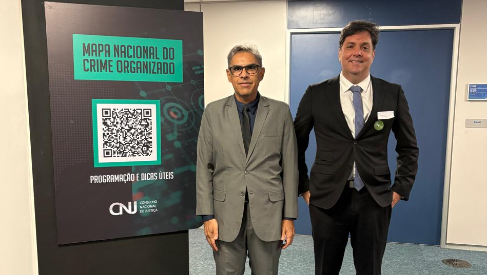 Imagem mostra os juízes Jossanner Nery Nogueira Luna e Antônio Dantas de Oliveira Júnior em pé, lado a lado, próximos a uma placa com o nome Mapa Nacional do Crime Organizado, em espaço interno do CNJ