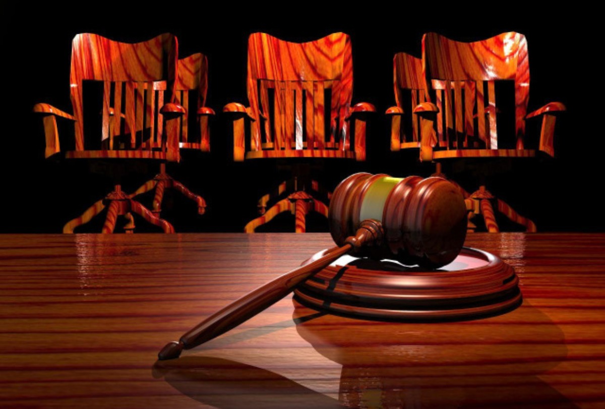 Martelo de juiz e três cadeiras ao fundo em alusão ao tribunal do júri